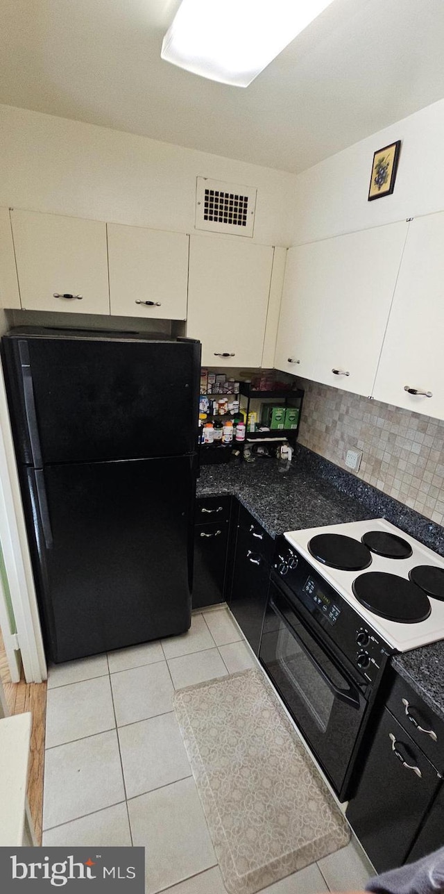 kitchen with tasteful backsplash, black fridge, electric stove, light tile patterned floors, and white cabinets