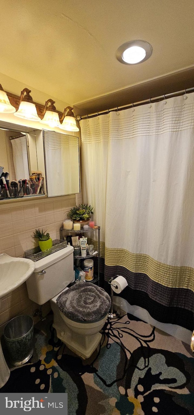 bathroom featuring toilet, tile walls, and tasteful backsplash