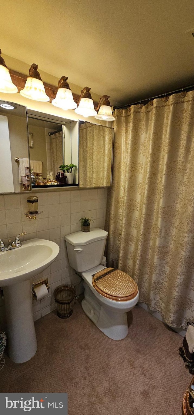 bathroom with toilet, tile walls, and sink