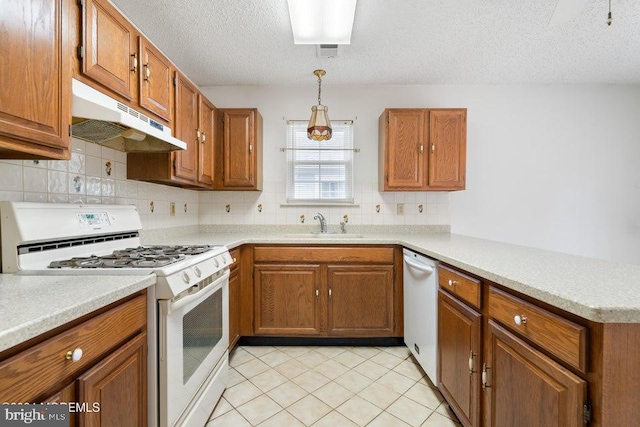 kitchen with backsplash, white appliances, a textured ceiling, sink, and pendant lighting