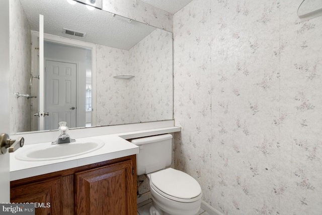 bathroom with vanity, toilet, and a textured ceiling