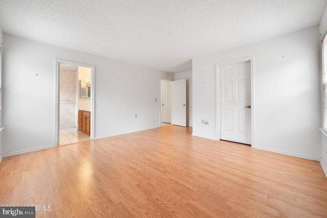 unfurnished room featuring a textured ceiling and light hardwood / wood-style floors