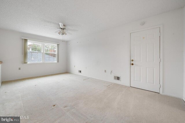 empty room featuring light carpet, a textured ceiling, and ceiling fan