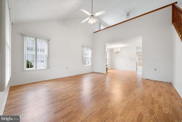 unfurnished living room featuring high vaulted ceiling, a textured ceiling, and light wood-type flooring