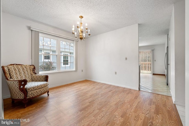 living area featuring a chandelier, light hardwood / wood-style floors, and a textured ceiling