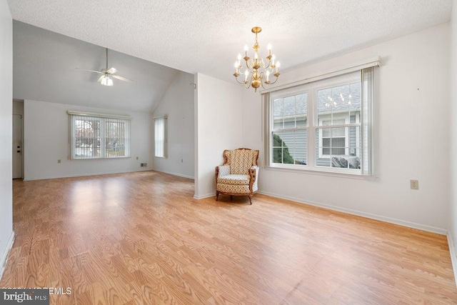 unfurnished room with a textured ceiling, a healthy amount of sunlight, lofted ceiling, and light hardwood / wood-style floors