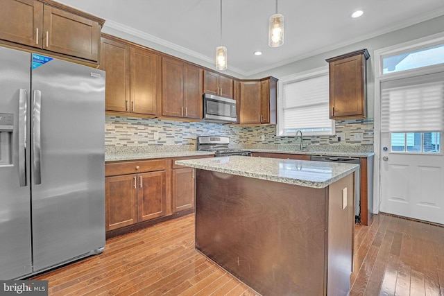 kitchen with light stone countertops, tasteful backsplash, stainless steel appliances, crown molding, and hanging light fixtures