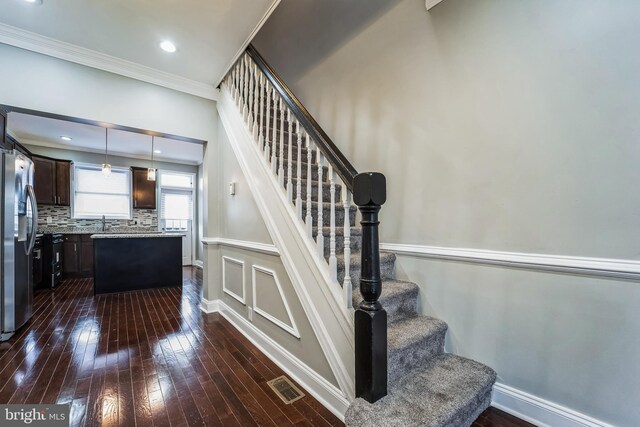 stairs with crown molding, sink, and hardwood / wood-style flooring