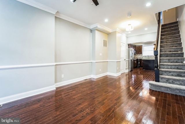 unfurnished living room featuring crown molding, sink, and dark wood-type flooring