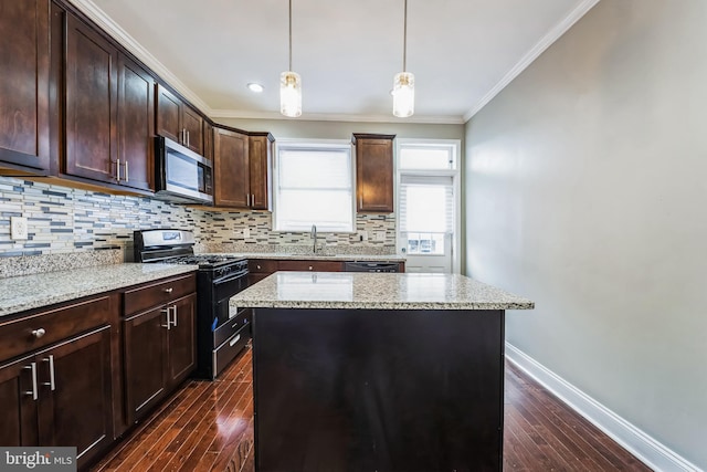 kitchen featuring light stone countertops, appliances with stainless steel finishes, a kitchen island, and ornamental molding