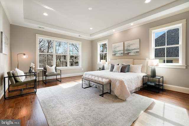 bedroom with hardwood / wood-style flooring and a tray ceiling