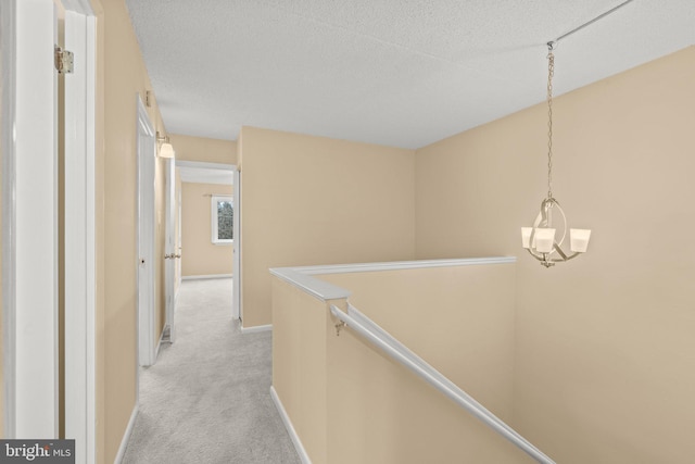 hallway featuring a textured ceiling and light colored carpet