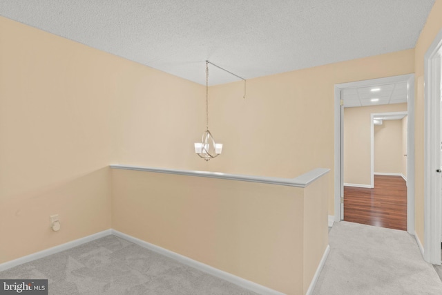 corridor with light carpet and a textured ceiling