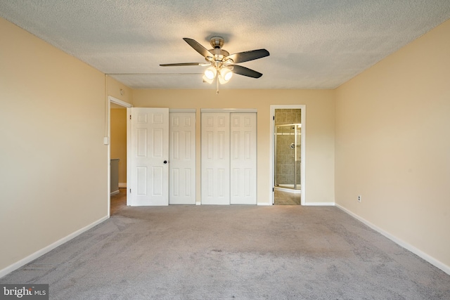 unfurnished bedroom with carpet flooring, ceiling fan, ensuite bathroom, and a textured ceiling