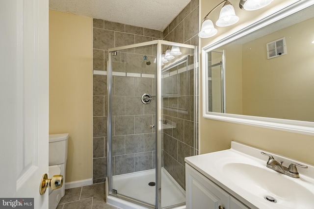 bathroom with tile patterned floors, a textured ceiling, toilet, a shower with door, and vanity