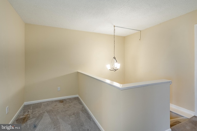 hall with light carpet, a textured ceiling, and an inviting chandelier