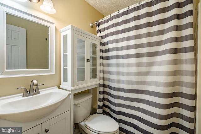 bathroom with vanity, a textured ceiling, toilet, and walk in shower