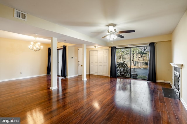 unfurnished living room with ceiling fan with notable chandelier and dark hardwood / wood-style flooring