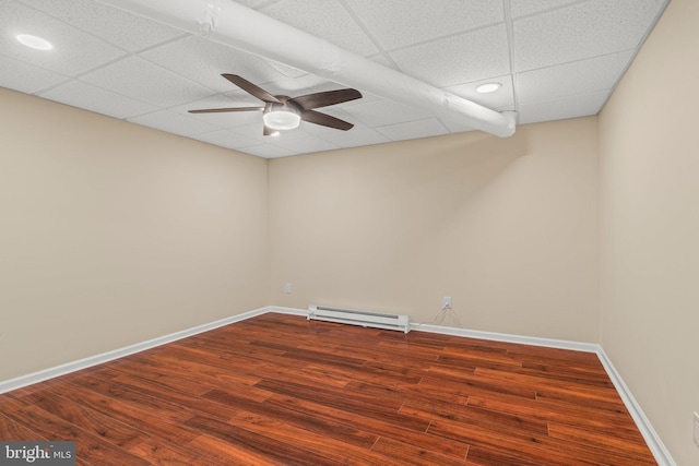 spare room featuring a drop ceiling, hardwood / wood-style flooring, baseboard heating, and ceiling fan