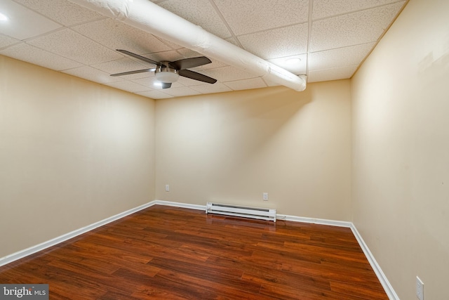 spare room with a drop ceiling, a baseboard radiator, hardwood / wood-style flooring, and ceiling fan