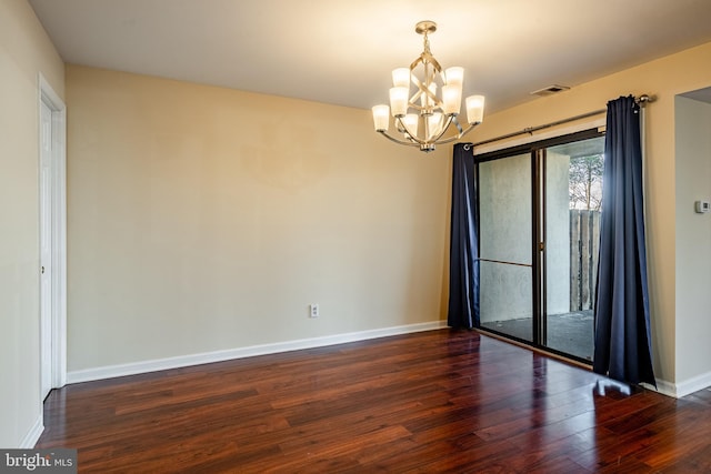 empty room with dark hardwood / wood-style flooring and a chandelier