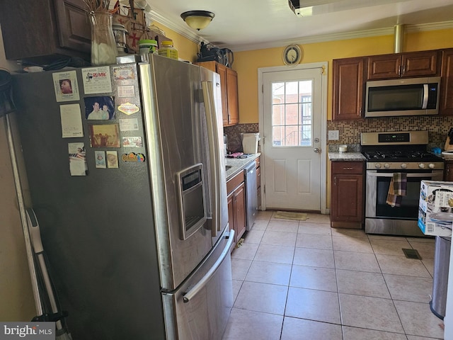 kitchen with tasteful backsplash, crown molding, light tile patterned floors, and stainless steel appliances