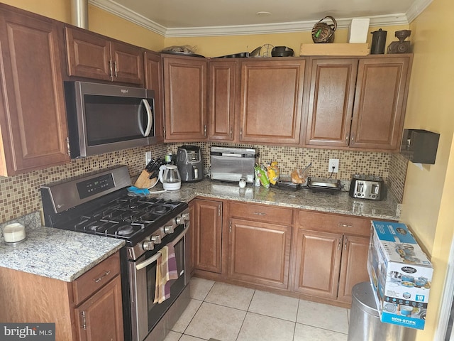 kitchen featuring appliances with stainless steel finishes, dark stone counters, and ornamental molding