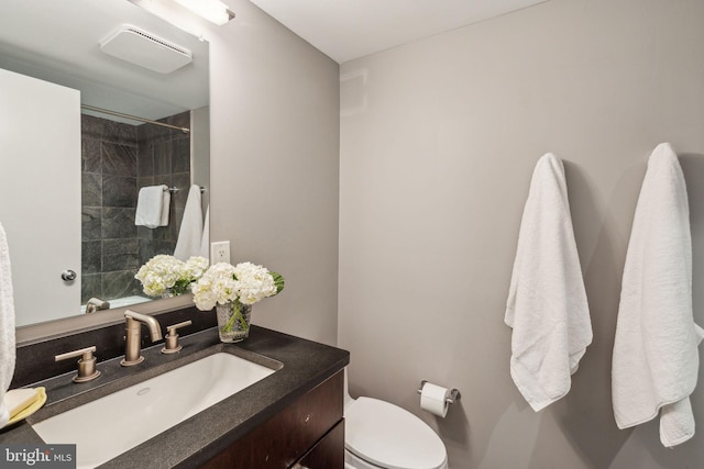 bathroom featuring vanity, tiled shower, and toilet