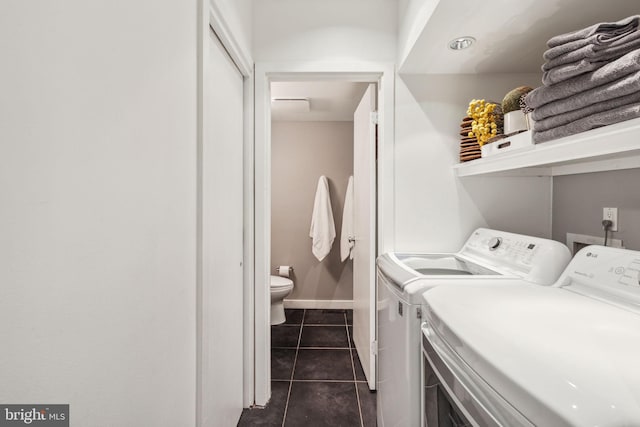 laundry room with dark tile patterned flooring and washer and clothes dryer