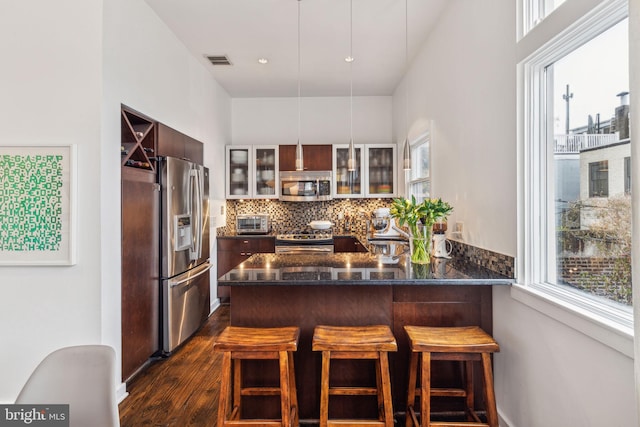 kitchen with appliances with stainless steel finishes, decorative backsplash, a kitchen bar, and kitchen peninsula