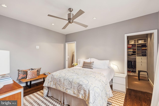 bedroom with hardwood / wood-style flooring, ceiling fan, a spacious closet, and a closet