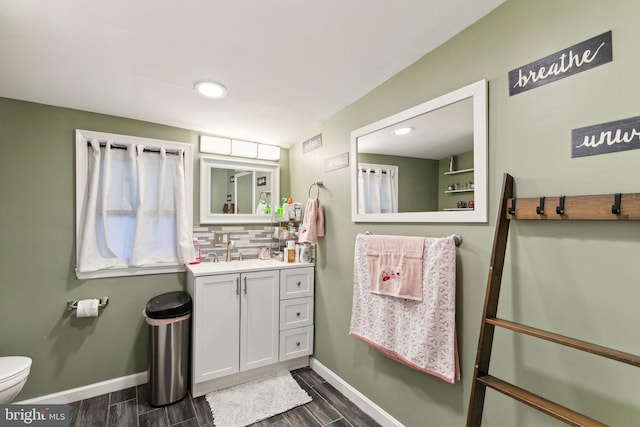 bathroom with hardwood / wood-style flooring, decorative backsplash, toilet, and vanity