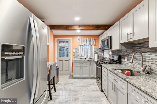 kitchen with light stone countertops, appliances with stainless steel finishes, tasteful backsplash, sink, and beam ceiling