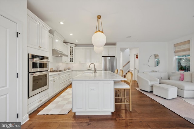 kitchen with white cabinetry, a kitchen island with sink, dark hardwood / wood-style floors, and appliances with stainless steel finishes