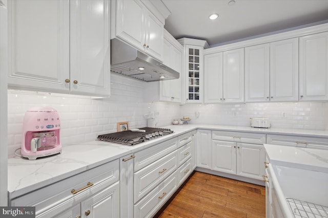 kitchen featuring stainless steel gas stovetop, light hardwood / wood-style floors, decorative backsplash, and white cabinetry