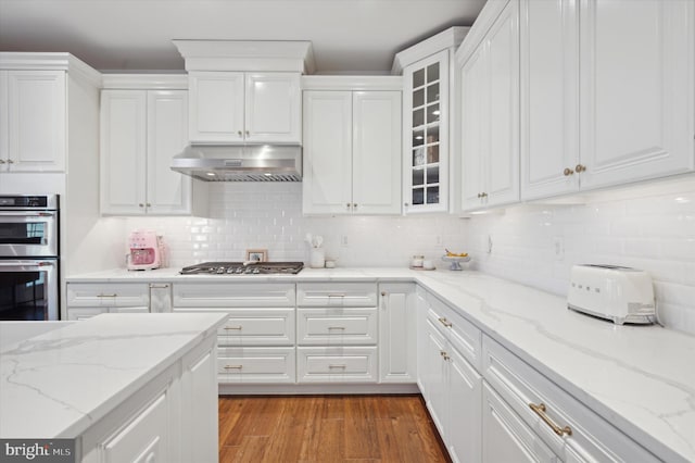 kitchen featuring hardwood / wood-style flooring, light stone counters, white cabinetry, and appliances with stainless steel finishes