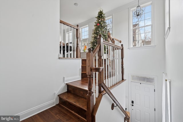 stairs featuring hardwood / wood-style floors, plenty of natural light, crown molding, and a notable chandelier