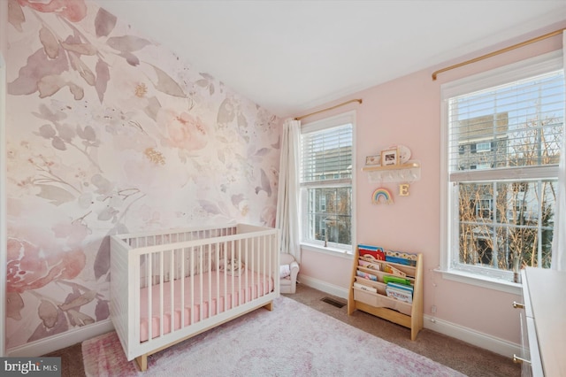 bedroom featuring carpet flooring, a crib, and multiple windows