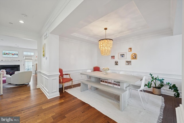 dining area with a notable chandelier, dark hardwood / wood-style floors, a raised ceiling, and ornamental molding