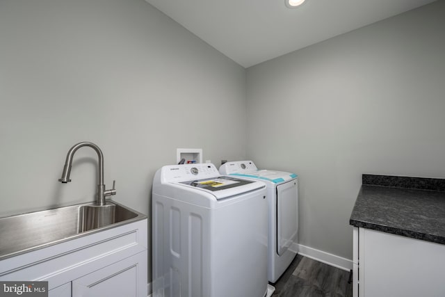 washroom featuring washing machine and clothes dryer, sink, dark hardwood / wood-style floors, and cabinets