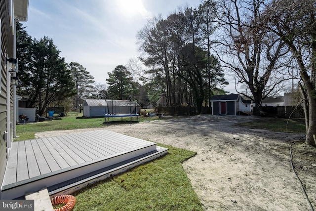 view of yard with a storage unit, a trampoline, and a wooden deck