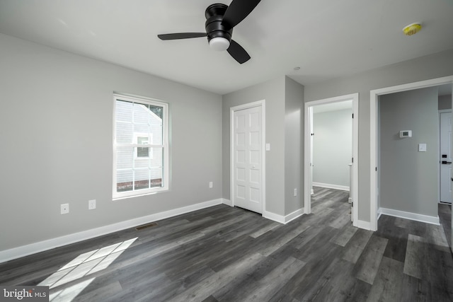 unfurnished bedroom featuring ceiling fan, a closet, and dark wood-type flooring