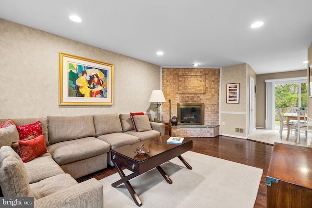 living room featuring a brick fireplace and hardwood / wood-style floors