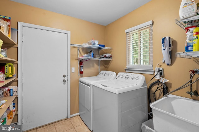 laundry area with sink, light tile patterned floors, and washer and clothes dryer