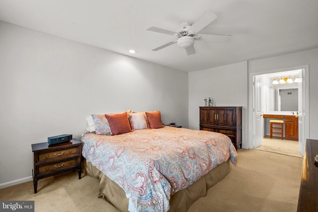 bedroom with ensuite bath, light colored carpet, and ceiling fan