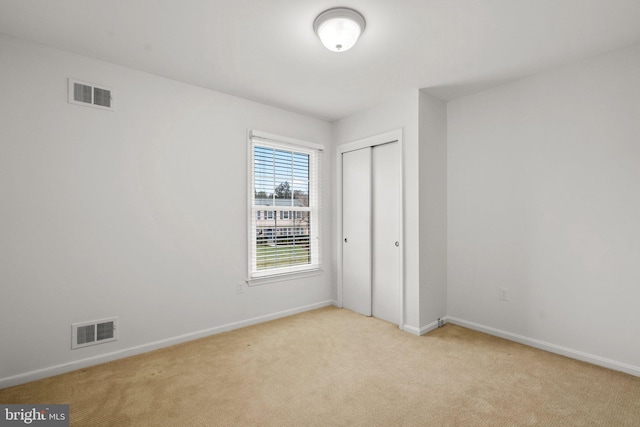 unfurnished bedroom with light carpet and a closet