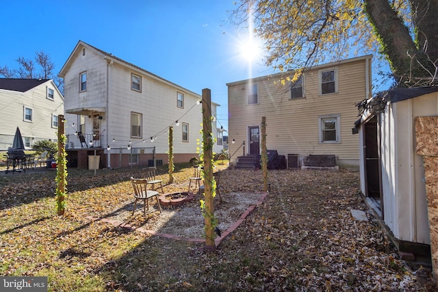 rear view of property featuring central AC and an outdoor fire pit