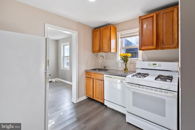 kitchen featuring dark wood-type flooring, sink, a healthy amount of sunlight, and white appliances