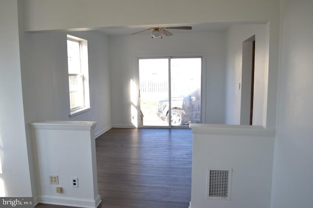 unfurnished living room featuring ceiling fan, a healthy amount of sunlight, and dark hardwood / wood-style flooring