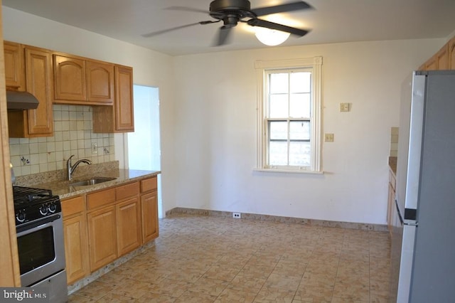 kitchen featuring sink, stainless steel gas range, tasteful backsplash, light stone counters, and white refrigerator